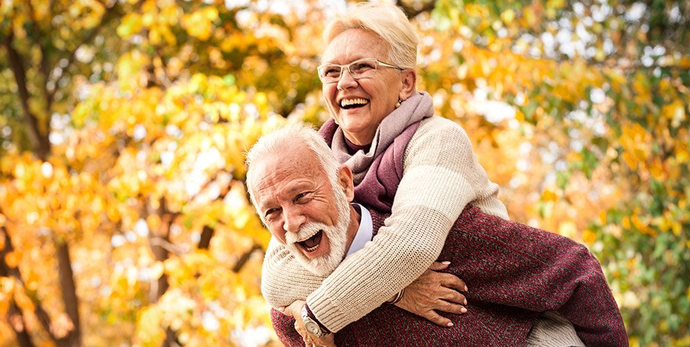 Älteres Paar ist glücklich vor gelb gefärbten Laubbäumen